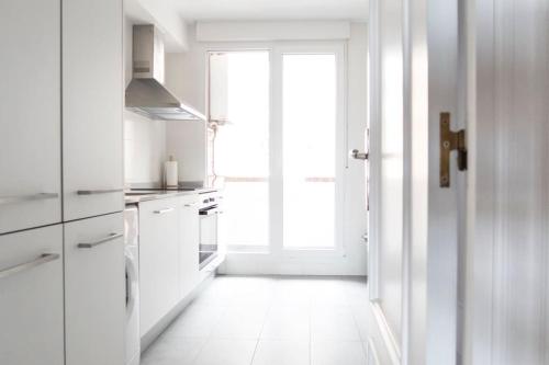 eine Küche mit weißen Schränken und einem großen Fenster in der Unterkunft Piso Avenida de los Castros - Sardinero in Santander