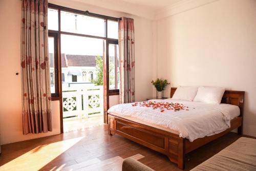 Un dormitorio con una cama con rosas. en Vang Anh Homestay Hoi An, en Hoi An