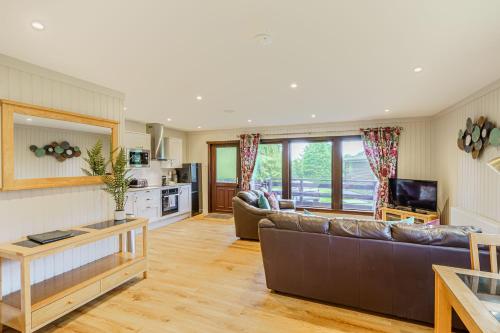 a living room with a couch and a table at Bluebell Lodge 10 with Hot Tub in Newton Stewart