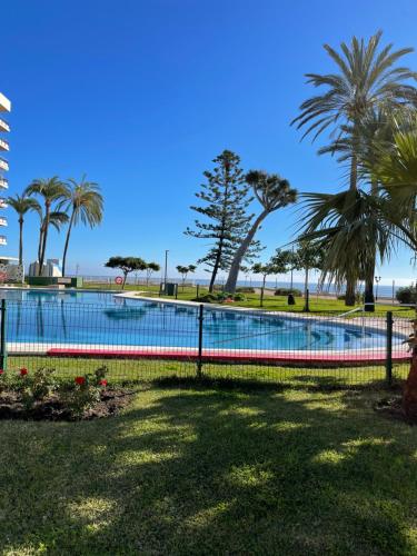 a swimming pool with palm trees and the ocean at Paraíso sobre el Mar Torremolinos Santa Clara in Torremolinos