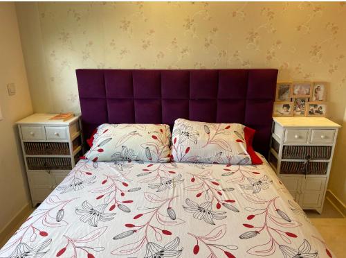 uma cama com uma cabeceira roxa num quarto em Ryad martil em Martil