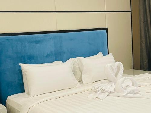 uma cama branca com lençóis e almofadas brancos em KLCC Suites Platinum 2 em Kuala Lumpur