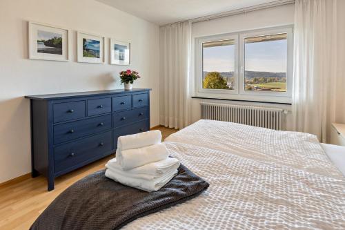 a bedroom with a bed with a blue dresser and two windows at Fewo Stempel in Küssaberg