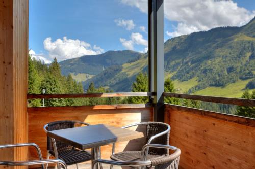 a table and chairs on a balcony with a view of mountains at Hölderle Damüls in Damuls