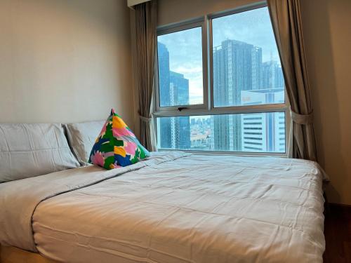 a bed with a pillow in front of a window at Belle Rama9 精品公寓 in Bangkok