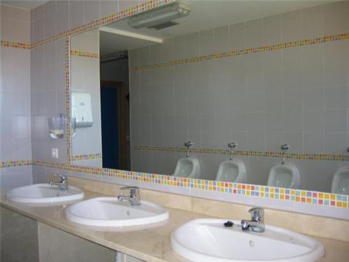 Baño público con 3 lavabos y espejo en Albergue Socfer, en Salamanca