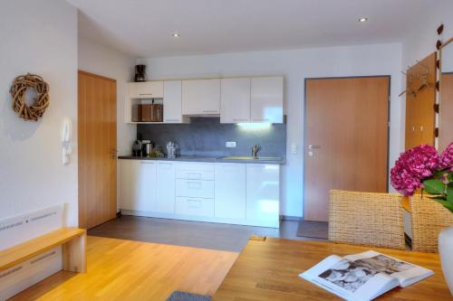 a kitchen with white cabinets and a table at Hölderle Damüls in Damuls