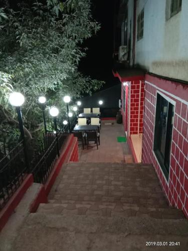 a patio at night with a table and chairs at Altaf's motel in Matheran