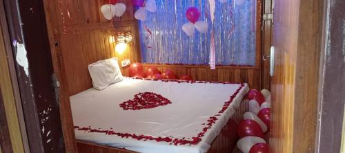 a cake with a heart on it in a room with balloons at Altaf's motel in Matheran