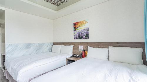 two beds in a room with white walls at 全新完工 台中逢甲飯店 九九商旅 台中包層台中包棟飯店 台中國旅卡 出差統編可 in Taichung