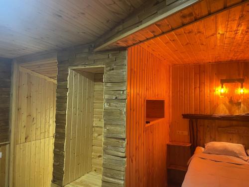 1 dormitorio con 1 cama en una pared de madera en Qusha Guesthouse Meeting in the mountains and views, en Kazbegi