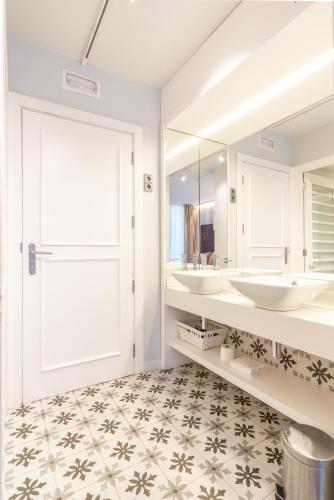 a bathroom with two sinks and a mirror at Serennia Fira Gran Via Exclusive Rooms in Hospitalet de Llobregat