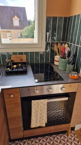 Il comprend une cuisine équipée d'une cuisinière. four supérieur à côté d'une fenêtre dans l'établissement Studio 2 pers aux inspirations 60s, à Chalon-sur-Saône