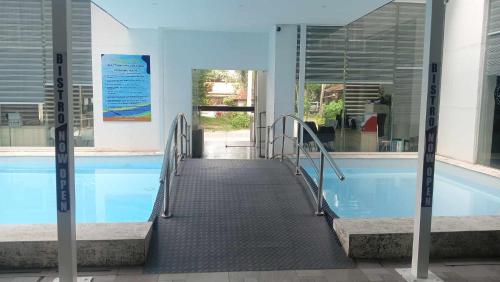 a swimming pool with a walkway next to a building at Chequers Suites Subic Bay in Olongapo