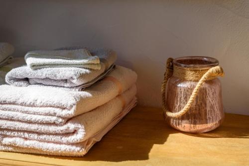 uma pilha de toalhas numa mesa ao lado de um frasco em Saint Esprit em Saint-Tropez