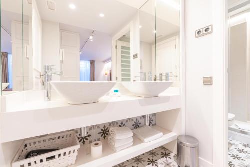 a white bathroom with two sinks and a mirror at Serennia Fira Gran Via Exclusive Rooms in Hospitalet de Llobregat
