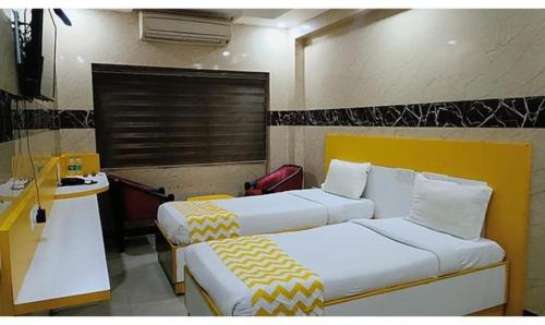 a hotel room with two beds and a desk at Hotel Stalin Pleasant Park - Triplicane in Chennai