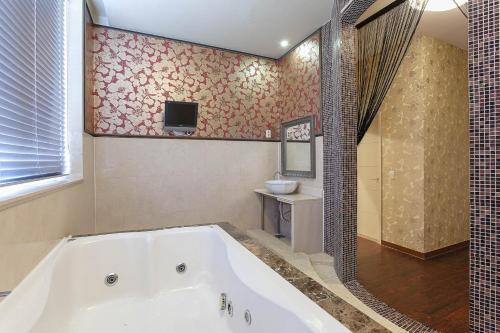 a bathroom with a tub and a tv on the wall at Carlton Hotel in Paju