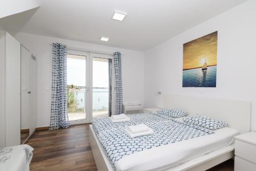 a white bedroom with a large bed and a window at Villa Miri in Privlaka