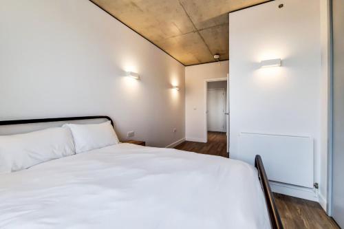 a bedroom with a white bed and a white wall at Repton Gardens at Wembley Park in London