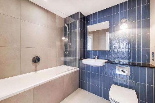 a bathroom with a tub and a sink and a toilet at Botanical-inspired apartments at Repton Gardens right in the heart of Wembley Park in London