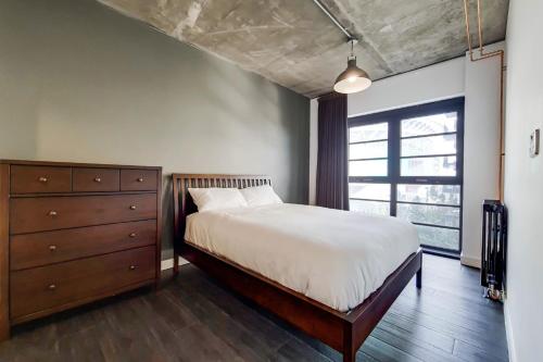 ein Schlafzimmer mit einem Bett, einer Kommode und einem Fenster in der Unterkunft Modern and Chic Apartments at Ferrum near Wembley Park in London
