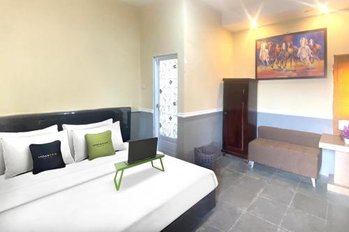 a bedroom with a bed with a laptop on it at Urbanview Hotel Syariah House of Tuwuh by RedDoorz in Tanjungkarang