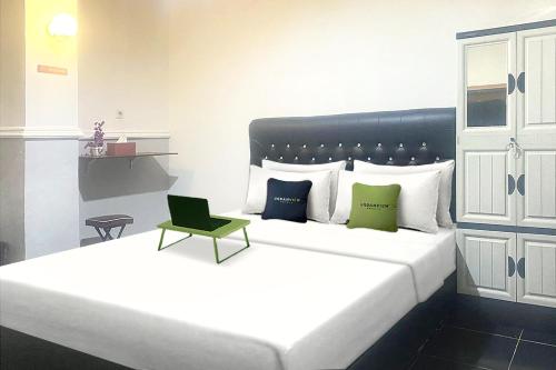 um quarto com uma grande cama branca com almofadas verdes em Urbanview Hotel Syariah House of Tuwuh em Tanjungkarang