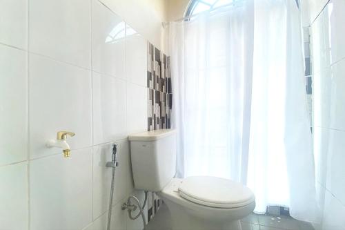 baño blanco con aseo y ventana en Urbanview Hotel Syariah House of Tuwuh, en Tanjungkarang