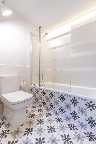 a bathroom with a toilet and a tub and a tile floor at Serennia Fira Gran Via Exclusive Rooms in Hospitalet de Llobregat