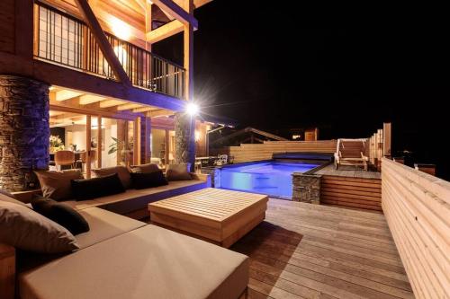 a patio with a couch and a swimming pool at night at Chalet Béla Vya 5 étoiles luxe Ski & Spa in Bourg-Saint-Maurice