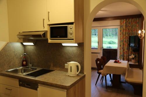 a kitchen with a sink and a microwave and a table at Ferienhaus Brigitte in Längenfeld