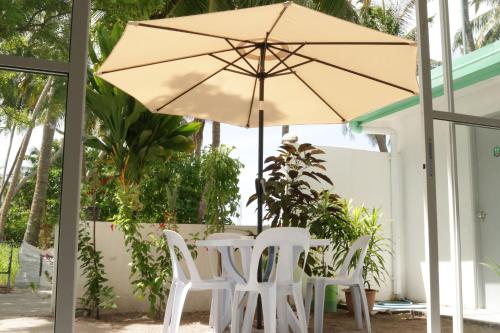 a table and two chairs and an umbrella at Empyrean Stay, Maldives in Thulusdhoo