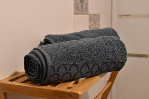 une pile de serviettes grises assises sur un portant en bois dans l'établissement Appartement 32 m2 intra muros - WIFI - Netflix - Bureau, à Avignon