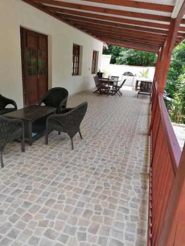 a patio with chairs and a table and tables at L’Habitation BoisNeuf in La Trinité
