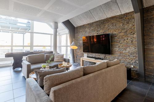 a living room with a couch and a television on a brick wall at Langeland luksuslejlighed med pool og spa in Rudkøbing