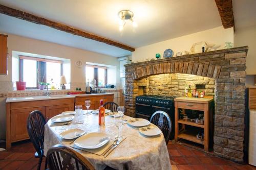 a dining room with a table and a stone fireplace at Midsummer Barn in Darwen