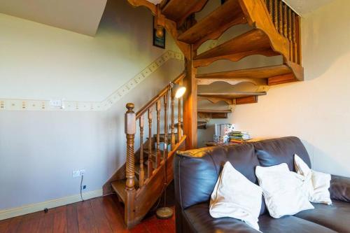 a brown leather couch in a living room with a staircase at Midsummer Barn in Darwen