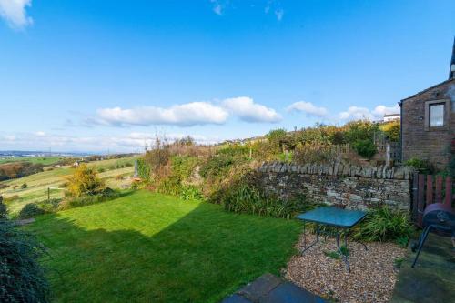 a garden with a stone wall and a bench at Midsummer Barn in Darwen