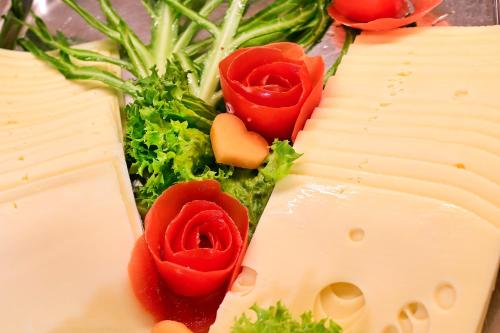 a bunch of cheese with three red roses on it at Hotel Rittergut Stoermede in Geseke