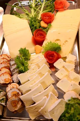 a tray with different types of cheese and vegetables at Hotel Rittergut Stoermede in Geseke