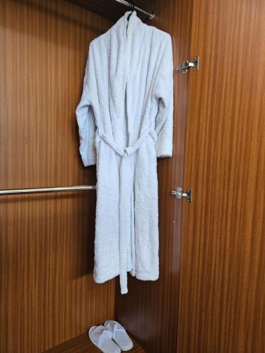 a white robe hanging on a wall in a bathroom at Cosy and accessible 1BR penthouse with terrace in Nairobi