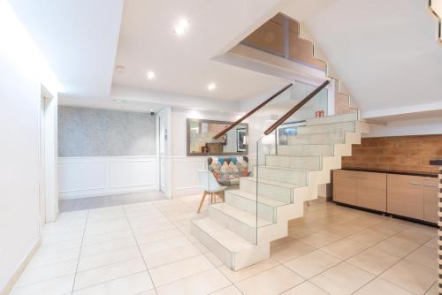 a staircase in a home with white walls and tile floors at Serennia Fira Gran Via Exclusive Rooms in Hospitalet de Llobregat