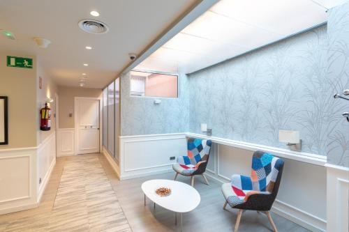 a hallway with two chairs and a table at Serennia Fira Gran Via Exclusive Rooms in Hospitalet de Llobregat