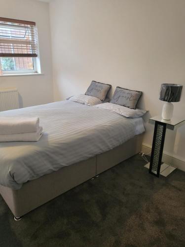 a bedroom with a large bed with white sheets and a television at THE NEST in Nottingham