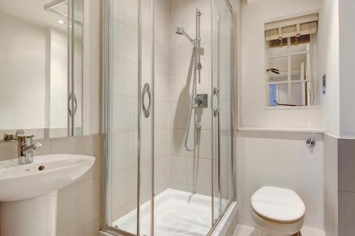 a bathroom with a shower and a toilet and a sink at Chelsea Pelham Apartments in London