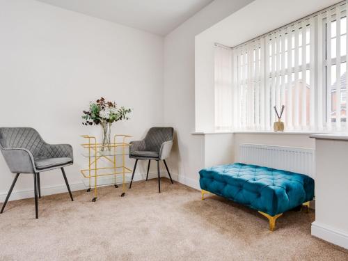 een woonkamer met 2 stoelen en een blauwe bank bij Pass the Keys Modern and Cozy Kirkby Retreat Parking Sleeps 5 in Knowsley