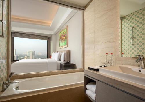 a bathroom with a tub and a sink and a bed at Trembesi Hotel in Serpong