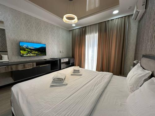 um quarto de hotel com uma cama grande e uma televisão de ecrã plano em VIP Hotel em Tashkent