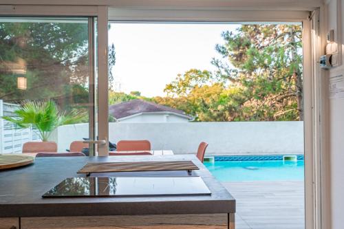 d'une terrasse avec une table et une vue sur la piscine. dans l'établissement Villa Comète - Maison de famille avec piscine, à Arcachon